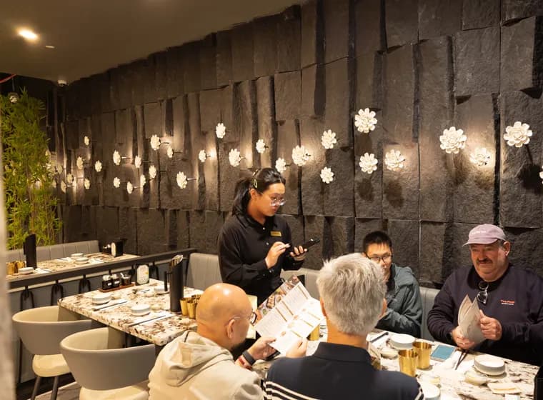 Guests dining beneath illuminated floral artwork at Supreme Dumplings Stonestown Galleria