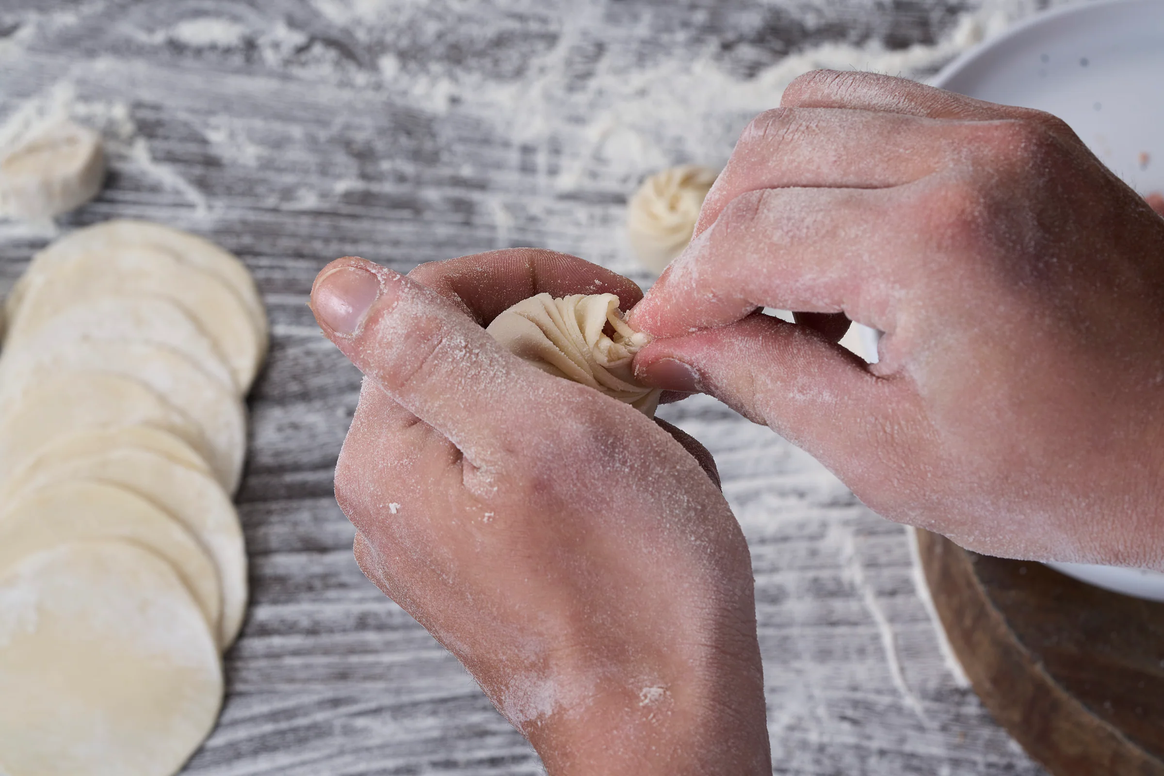 A chef pleating a delicate Xiao Long Bao wrapper by hand