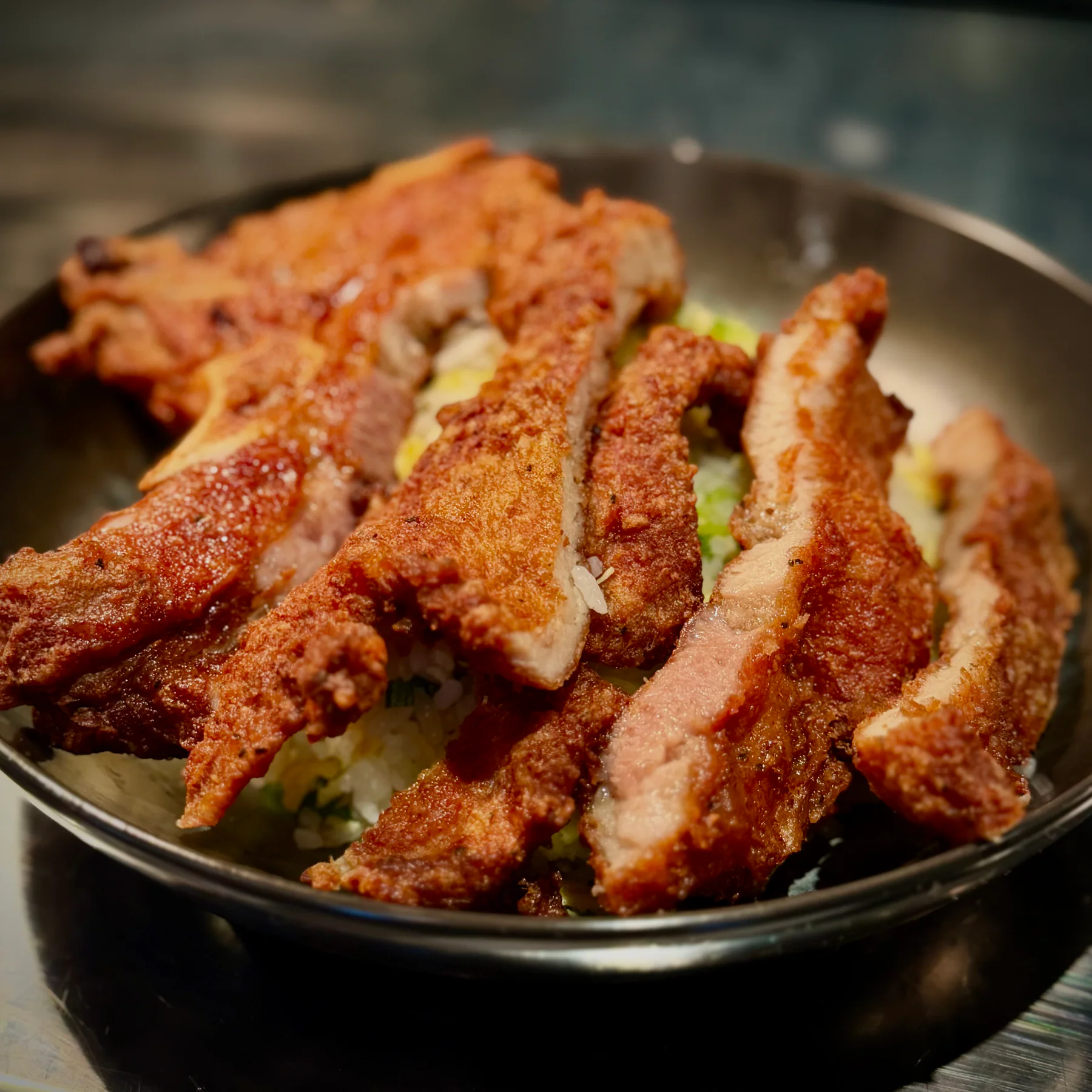 Golden fried pork chop sliced over rice