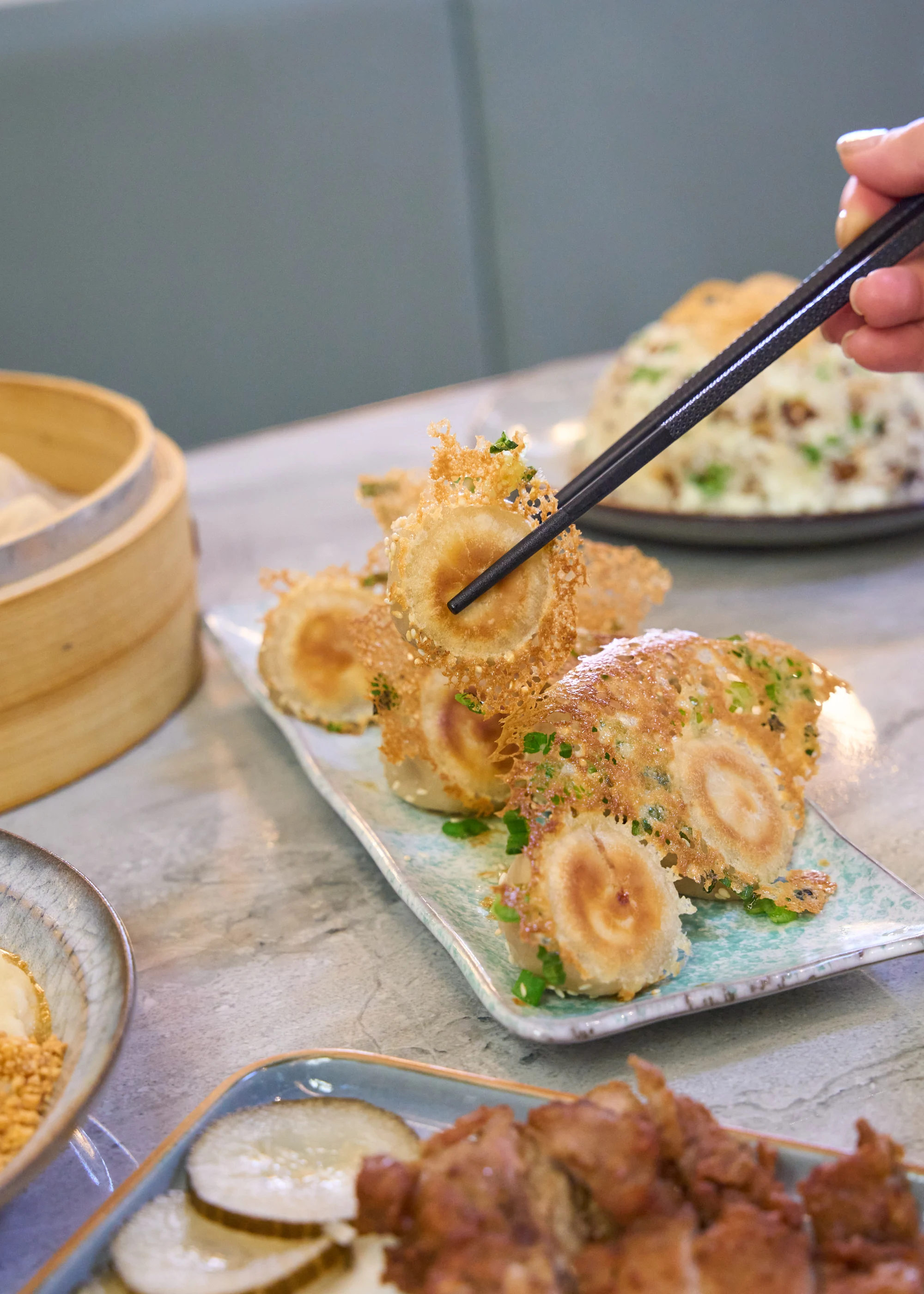 A pan-fried dumpling lifted from a plate at the table