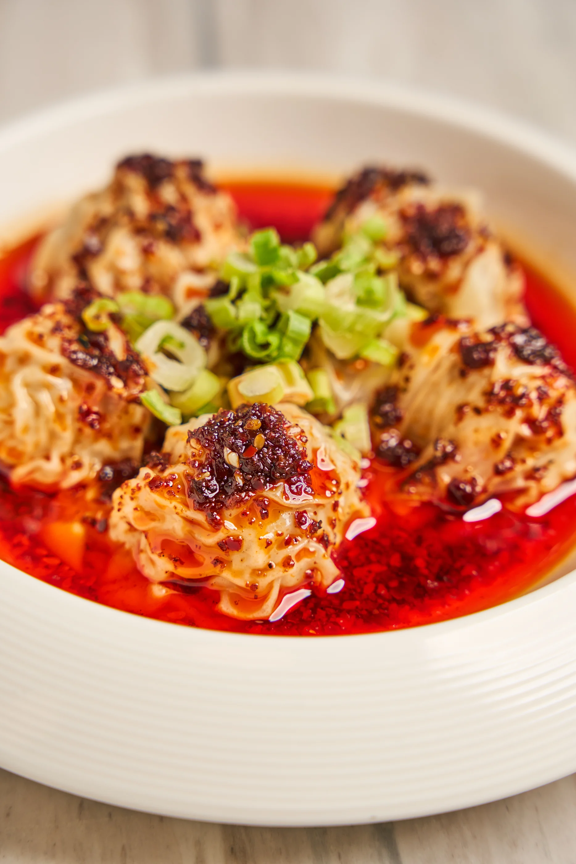 Spicy pork wontons finished with chili oil and scallions