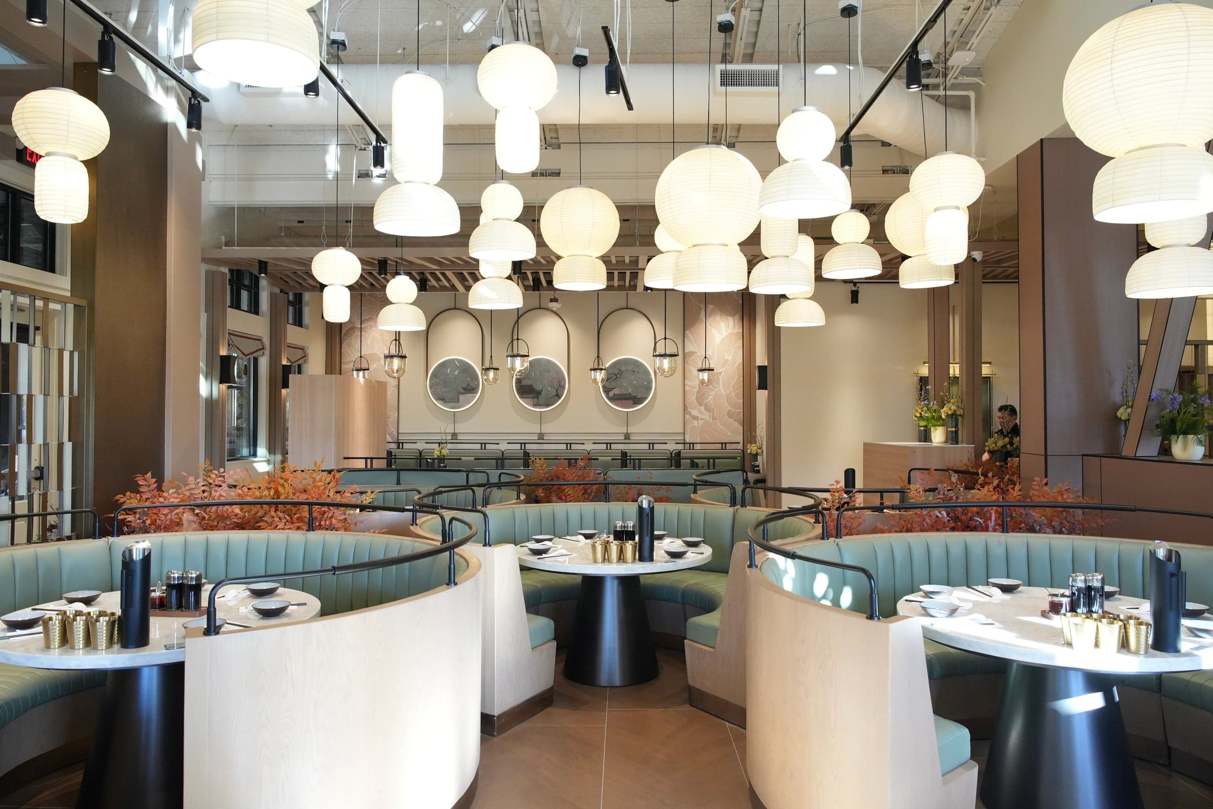 The Alderwood dining room: round sage booths beneath a ceiling of white paper lanterns