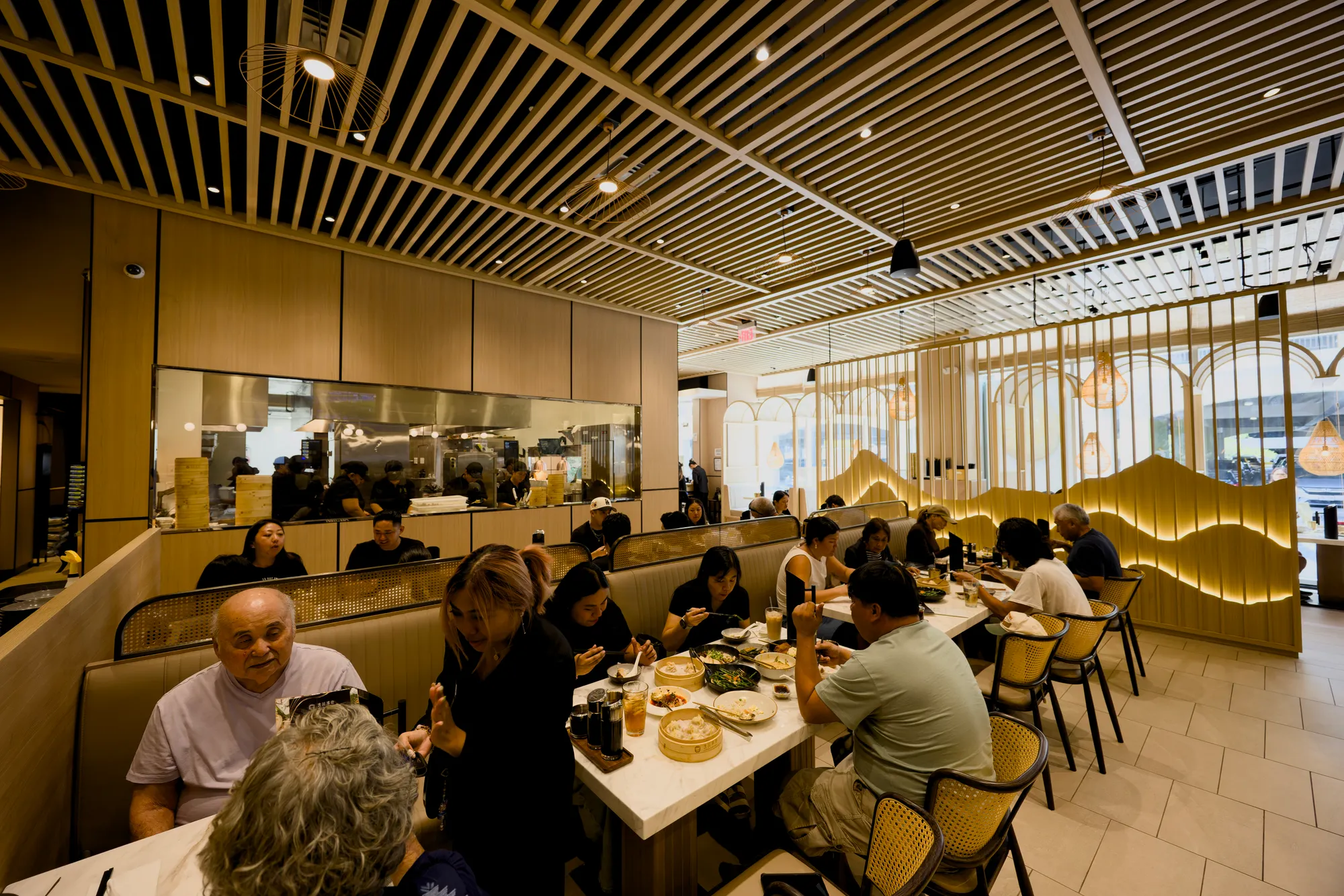 Guests sharing Xiao Long Bao in the busy Honolulu dining room, the open kitchen behind them