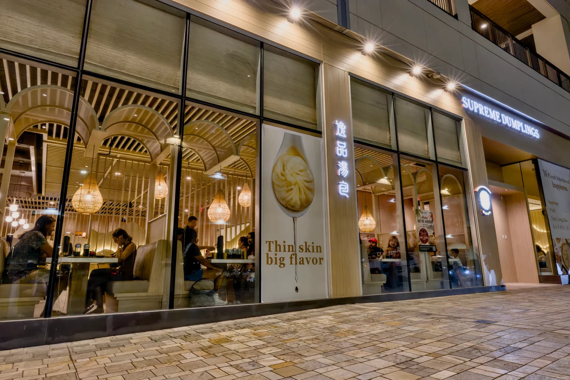 Supreme Dumplings storefront at Ala Moana Center, its dining room glowing behind tall windows