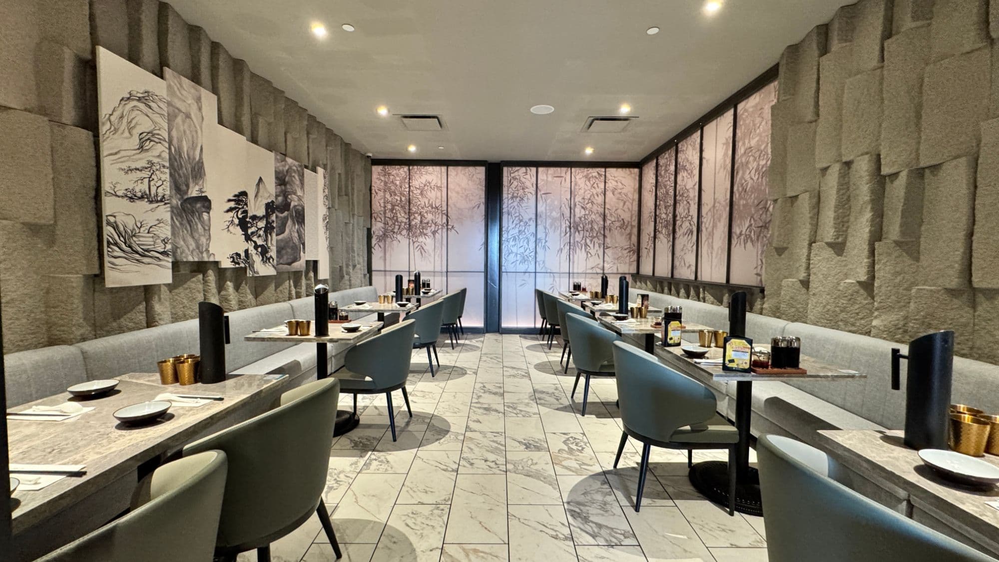 Tacoma's VIP Room 2: banquettes and tables on both sides of a marble aisle, ink-wash panels on the left and bamboo screens at the far end